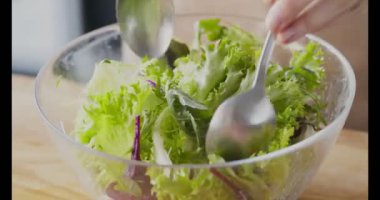 Taze sebze salatasıyla iki kaşığı karıştıran kadın.