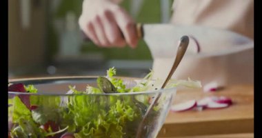 Kadın mutfakta sebze salatası için taze turp kesiyor.