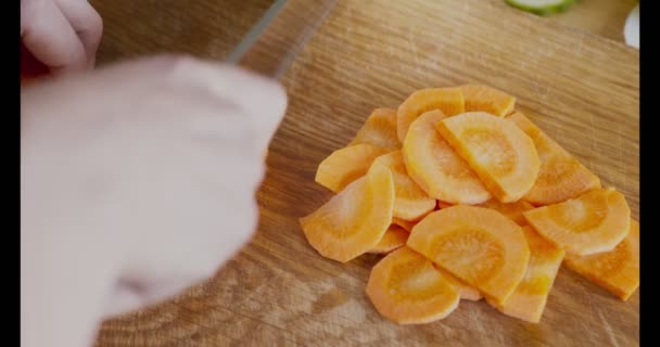 Γυναικεία χέρια που κόβουν φρέσκο καρότο σε ξύλο κοπής — Αρχείο Βίντεο