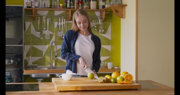 Mujer joven disfrutando de corte de manzana verde en la cocina — Vídeo de stock