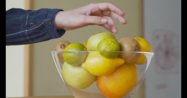 Ung kvinne som tar ferskt eple fra fruktfat på kjøkkenet – stockvideo