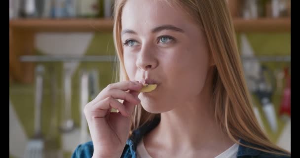 Молодая женщина наслаждается кусочком киви на кухне — стоковое видео