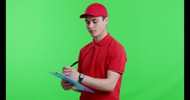 Evrakları dolduran, kameraya gülümseyen genç bir işçi.