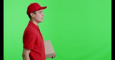 Kırmızı üniformalı neşeli teslimatçı paketle geliyor.