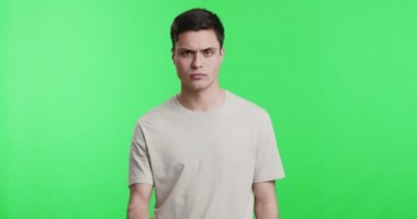 Genç ciddi bir adam kameraya tehdit ediyor, yumruğunu sallıyor.