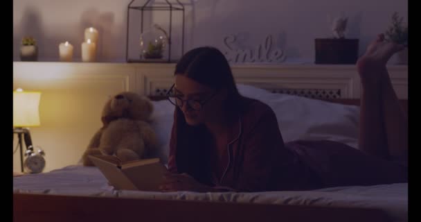 Vrouw die het boek leest voordat ze in bed slaapt — Stockvideo