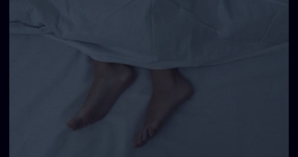 Feet of woman sleeping under duvet in bed at night, top view — Stock Video