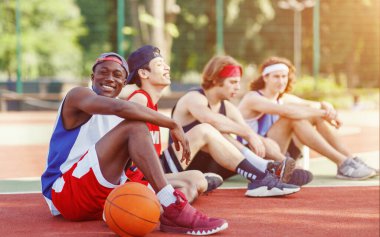 Group of millennial basketball players resting after match at outdoor court, empty space clipart