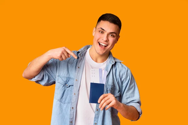 Веселый парень, указывающий на паспорт и билеты в руке — стоковое фото