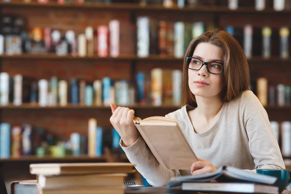 Soñando chica mirando hacia otro lado mientras estudia con libros —  Fotos de Stock