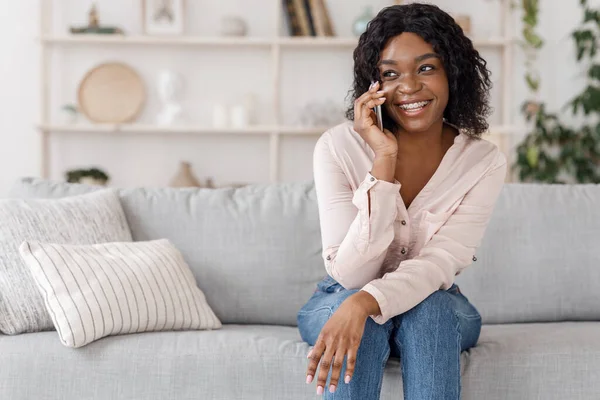Chica negra feliz hablando en el teléfono móvil, relajarse en el sofá en casa —  Fotos de Stock