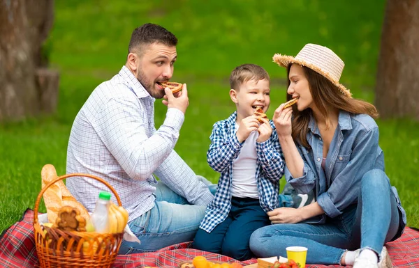 Los padres del milenio con su hijo comiendo trozos de pastel sabroso en el picnic de verano en el campo — Foto de Stock