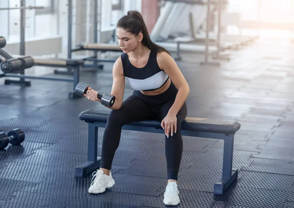 Ćwiczenia siłowe. Fit girl w odzieży sportowej ćwiczy z hantlami na siłowni — Zdjęcie stockowe