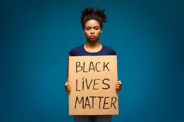 Afro-Amerikalı kadın elinde BLM yazılı bir pankart tutuyor.