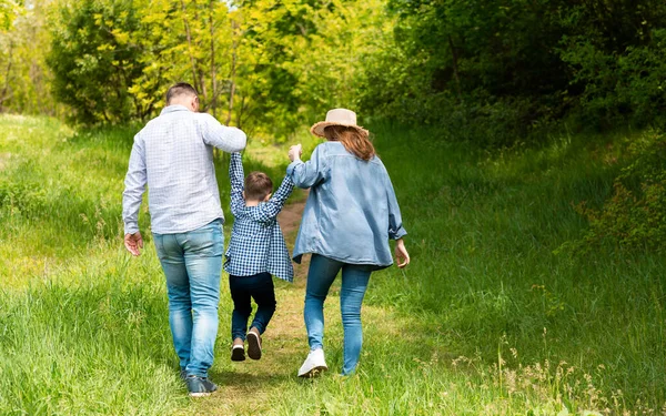 Widok z tyłu młodych rodziców na spacer z dzieckiem na wsi, przestrzeń kopiowania — Zdjęcie stockowe