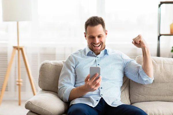 Excited male employee feeling ecstatic holding phone — Stock Photo, Image
