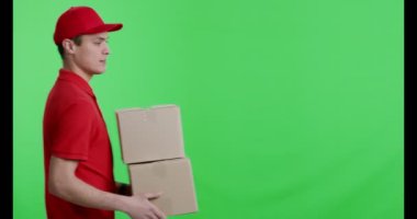 Kırmızı üniformalı genç kurye kameraya paket getiriyor.