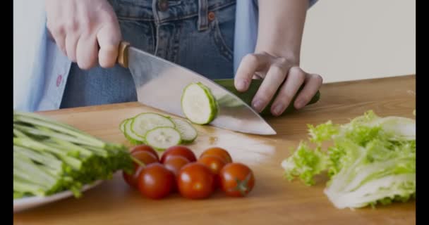 Mutfakta sebze salatası için salatalık kesen bir kadın. — Stok video