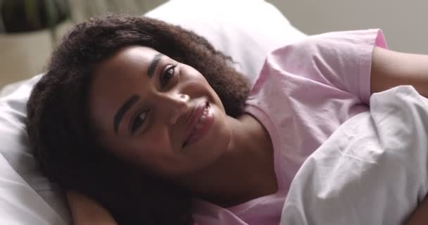Африканська американка усміхається перед камерою, лежачи в ліжку. — стокове відео