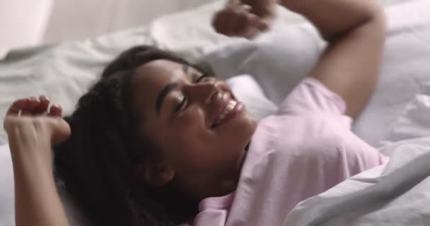 Gut ausgeruhte schwarze Frau dehnt sich morgens im Bett — Stockvideo