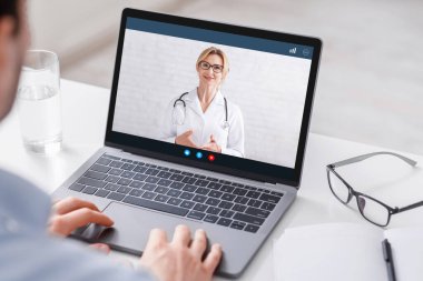 Evde modern tedavi. Adam bilgisayardan videolu doktorla izliyor.