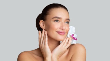 Beyaz orkide çiçeğiyle poz veren güzel kız.