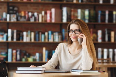 Akıllı telefonla konuşan ve gülümseyen çekici bir genç kız.