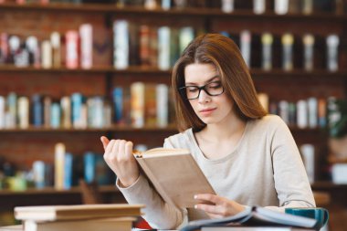 Genç kız kafeteryada kitap ve kahveyle boş zaman geçiriyor.
