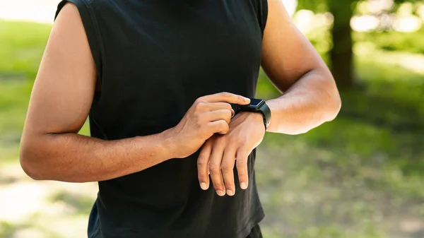 Vista de primer plano del joven chequeando su smartwatch o rastreador de fitness durante el entrenamiento al aire libre —  Fotos de Stock