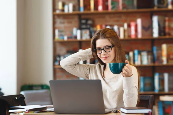 Menina em óculos usando laptop e beber café — Fotografia de Stock