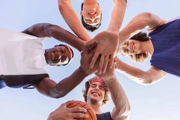 Widok dna szczęśliwy wielorasowy koszykówka zespół kładąc swoje ręce razem w jedności przed grą na zewnątrz — Zdjęcie stockowe