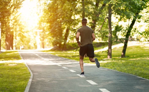 Pohled zezadu na tisíciletého sprintera při ranním běhu v parku za slunečného rána, prázdné místo — Stock fotografie