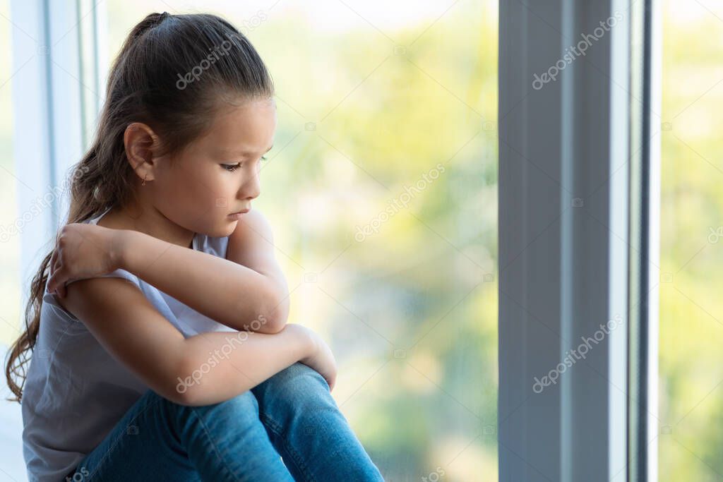 Unhappy Kid Girl Sitting Near Window Suffering From Loneliness Indoors