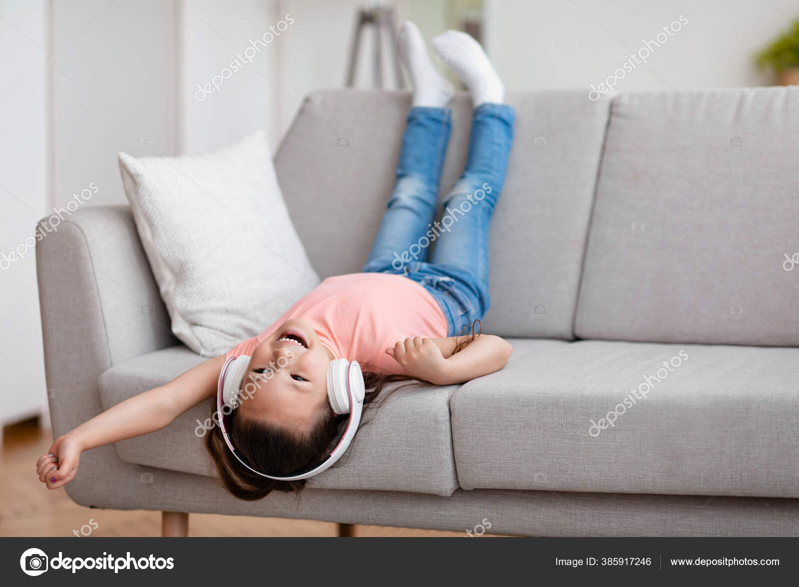 Menina ouvir música se divertindo sentado de cabeça para baixo no sofá  interior fotos, imagens de © Milkos #385917246