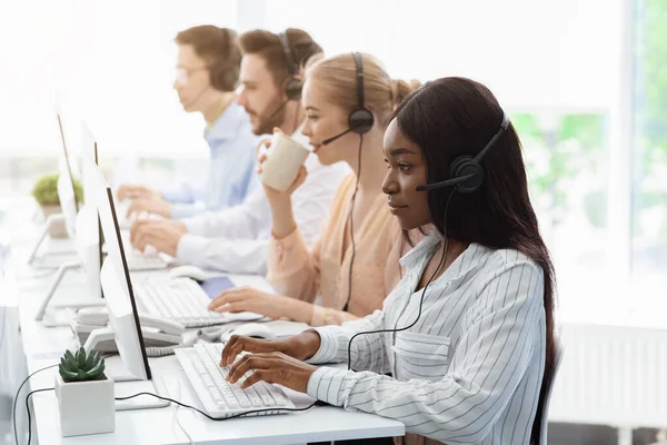 Funcionários da linha de call center com fones de ouvido trabalhando em computadores no escritório de espaço aberto — Fotografia de Stock