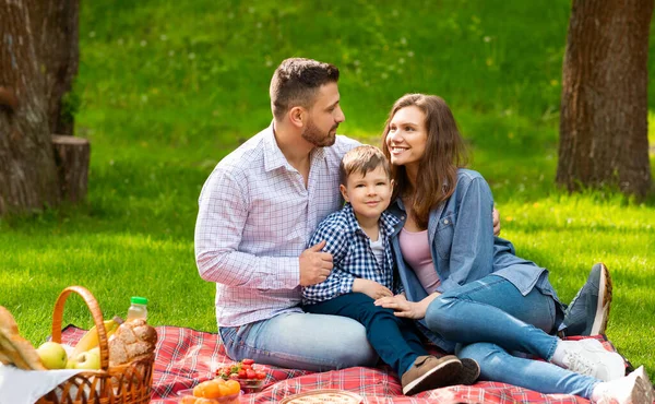 Família amorosa com bonito criança passar fim de semana juntos em piquenique no parque — Fotografia de Stock