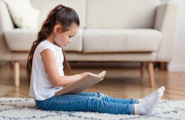 Hafta sonları evde oturmuş kitap okuyan bir kız.