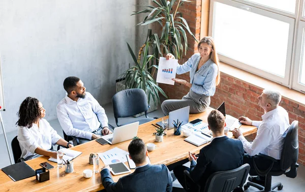 Zakenvrouw toont data grafieken aan medewerkers tijdens vergadering in Office — Stockfoto