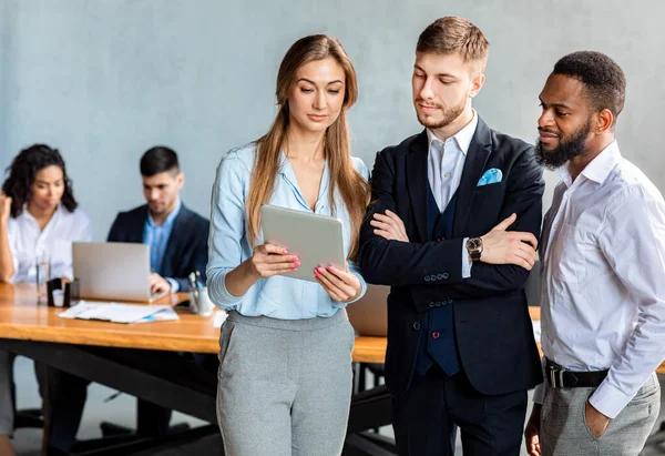 Femme d'affaires montrant la tablette à des collègues discutant des nouvelles d'affaires dans le bureau — Photo