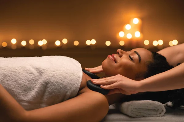 Therapist putting hot stones on african lady shoulders — Stock Photo, Image