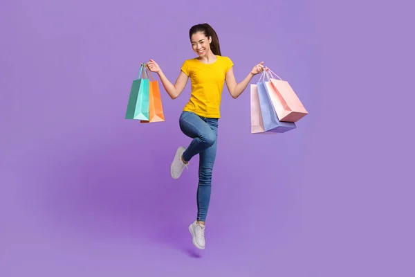季节性销售。快乐的年轻亚洲女孩提着购物袋跳到空中 — 图库照片