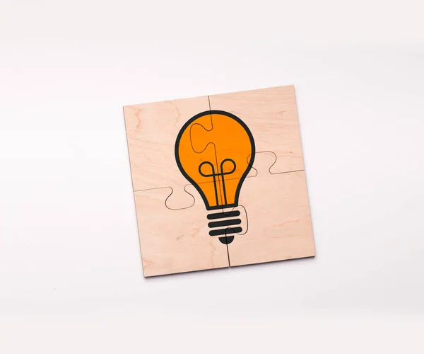 Creación de Ideas. Vista superior del rompecabezas de madera completado con bombilla de luz dibujada —  Fotos de Stock