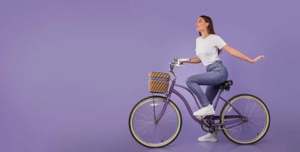 Beautiful girl riding her bike at purple studio, isolated — Stock Photo, Image