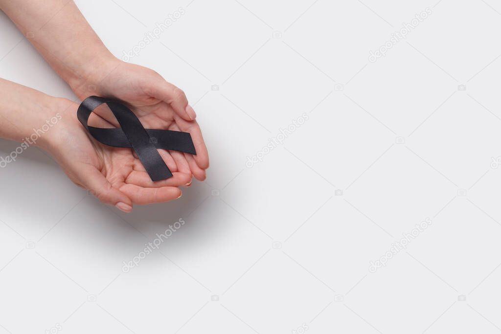 Black Awareness Ribbon in hands on white background
