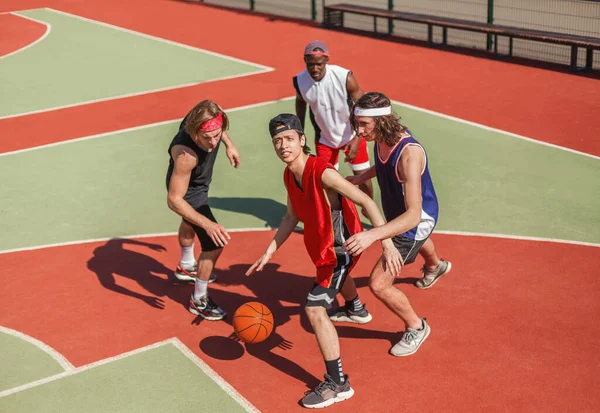 Team of professional basketball players fighting for ball on outdoor court