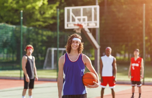 Atractivo jugador millennial y su equipo multinacional listo para jugar pelota en la cancha de baloncesto al aire libre — Foto de Stock