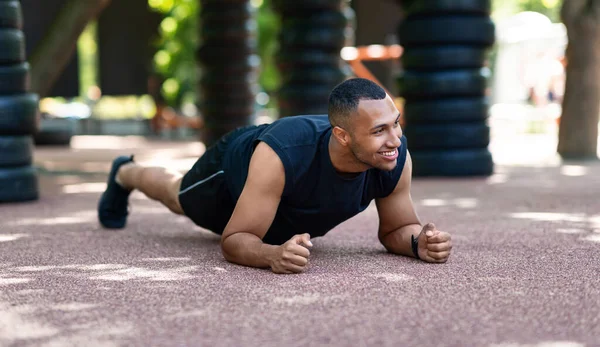 Afrikai amerikai kocogó csinál könyök deszka reggeli edzés után a Városligetben — Stock Fotó