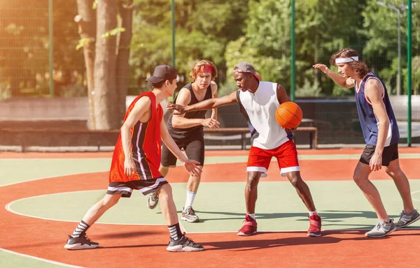 Equipo de deportistas milenarios que participan en el juego de baloncesto en la cancha al aire libre en verano — Foto de Stock
