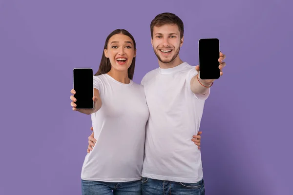 Cónyuges felices mostrando la pantalla del teléfono celular en blanco a la cámara — Foto de Stock