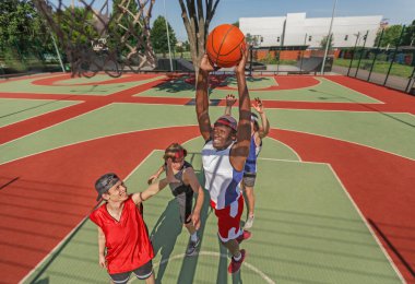 Siyahi basketbolcu gol atmak için atlıyor ve takımı açık sahada